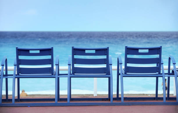 sillones azules en el "promenade des anglais" en niza en la riviera francesa frente al mar mediterráneo. - city of nice france beach promenade des anglais fotografías e imágenes de stock