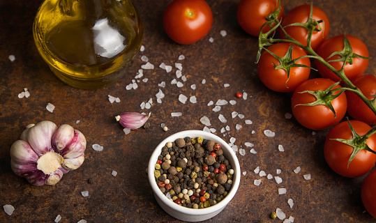 Fragrant spices are scattered on the table. Next to a sprig of cherry tomatoes and olive oil