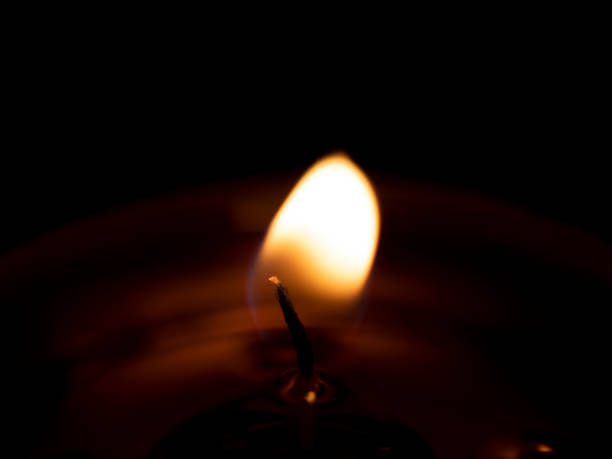 istock Burning candle flame close up black background 1405100493