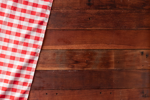 rustic wooden table background with red checkered tablecloth