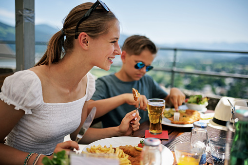 Kids eating wiener schnitzel in a open air restaurant in Salzburg with view on the surrounding mountains.\nCanon R5