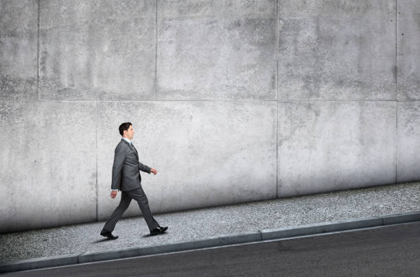 istock Businessman Walking Uphill On Sidewalk Next To Concrete Wall 1405113167