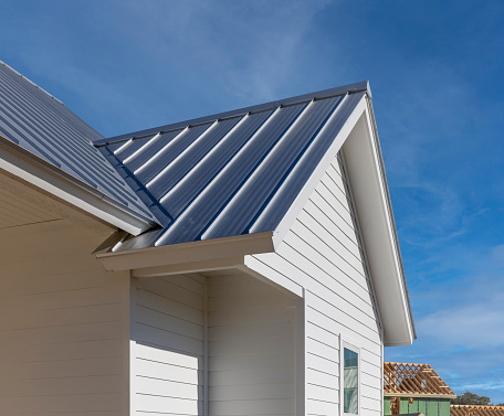 A black new roof and white siding of a house that is new and under construction.