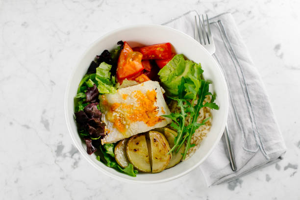 tazón de pescado de ensalada saludable. zander, verduras, hojas verdes, aguacate, tomate y arroz integral en un tazón. - dishware brown rice rice variation fotografías e imágenes de stock