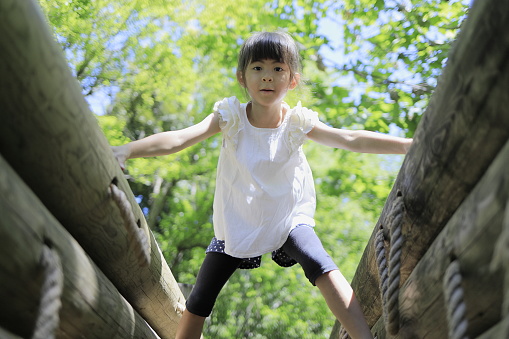 Japanese student girl playing at outdoor obstacle course (7 years old)