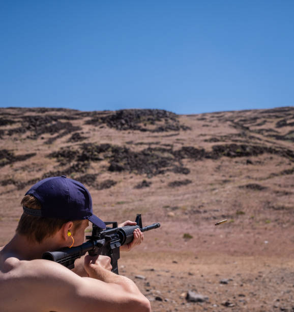 A young man shooting an assault style rifle in the Nevada desert.