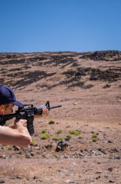 istock Young Man Shooting Assault Rifle in the Desert 1405142789