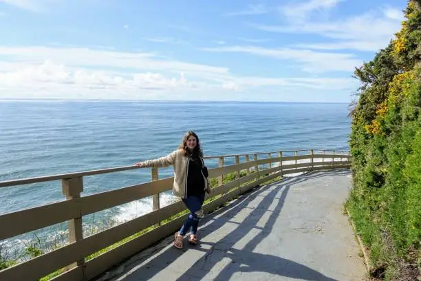 Photo of A young woman posing outside of the walkway towards the california sea lions cave outside Florence, Oregon, United States, with hundreds of sea lions living inside a huge sea cave