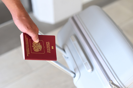 Una mano sosteniendo pasaporte ruso y maleta photo
