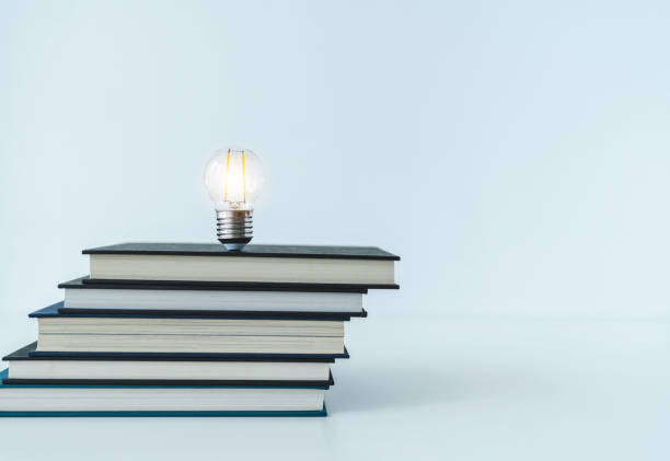 istock Glowing lightbulb or bright lamp with book or textbook. Skill improvement for student or businessperson. Studying and training course online at home. Business success idea, education learning concept 1405145363