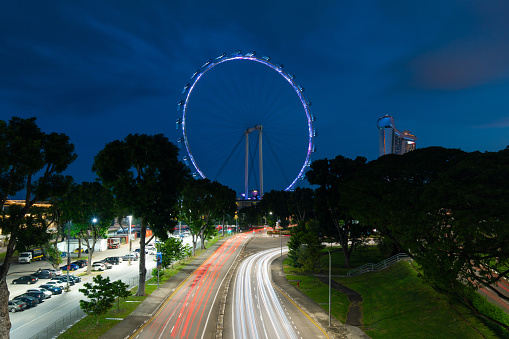 Singapore - May 23, 2022: Car trails around Singapore Flyer at night.