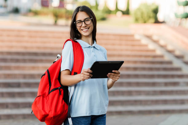 istock A student girl writes a message on her tablet while walking around the city 1405154682