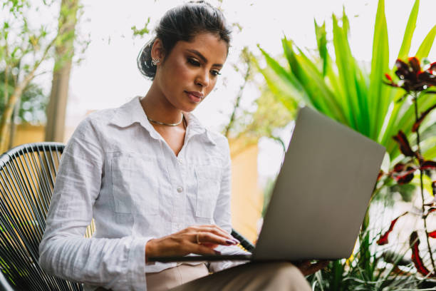istock Nomad on work. Confident young Latin woman making video call on laptop while sitting by window in cafe. 1405154716