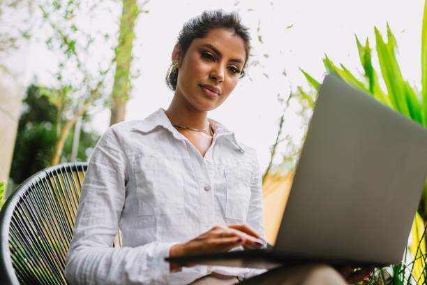 istock Nomad on work. Confident young Latin woman making video call on laptop while sitting by window in cafe. 1405154739