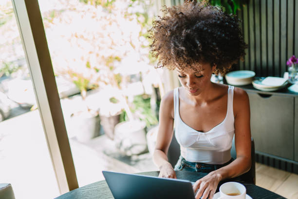 istock Nomad on work. Confident young Latin woman making video call on laptop while sitting by window in cafe. 1405155565