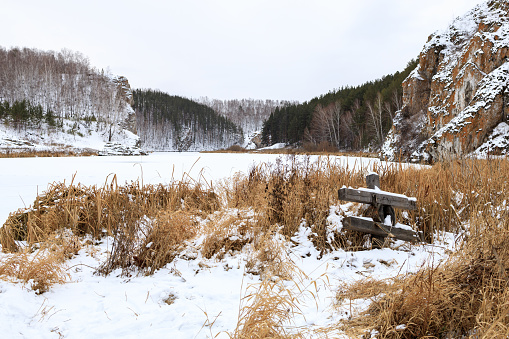 winter landscape on the bank of the river, dry grass on the bank and a wooden structure. rural landscape