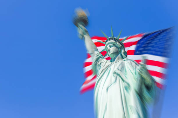 istock Statue of Liberty with a large american flag with motion blur effect 1405159406