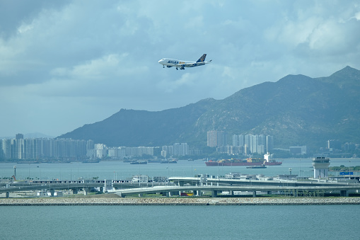 Airplane landing at Hong Kong international airport viewed from the town of Tung Chung on Lantau island.