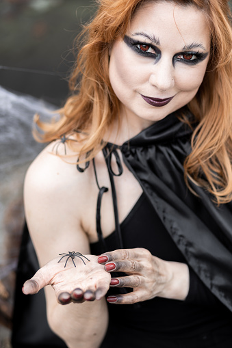 Woman with halloween style skull makeup, with blue hair on red and black background looking to the side and down