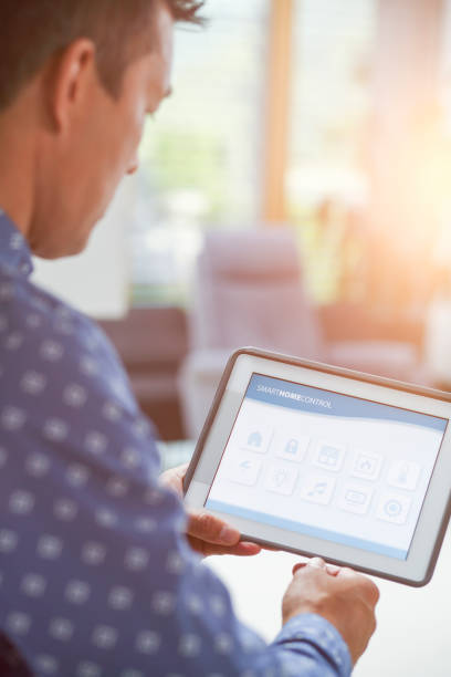 istock Man using smart home automation in living room with digital tablet 1405168586