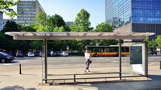 Public transport stop in the city with an empty place for an advertising poster banner. Near trees and houses. Horizontal orientation. High quality photo.