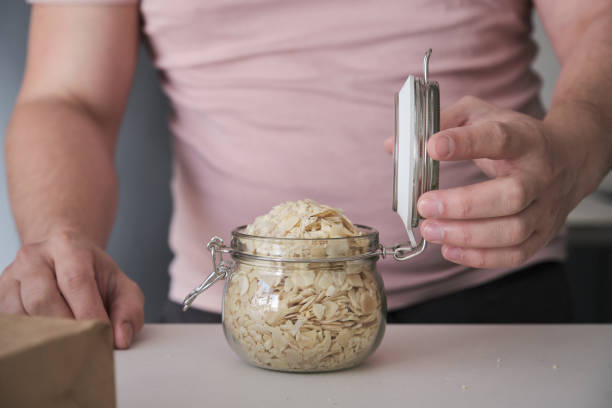 Unrecognizable latin man closing a jar full of blanched sliced almonds. Food in bulk delivery.