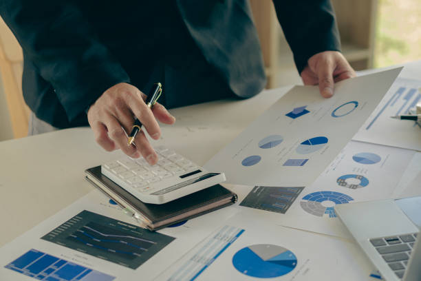 istock Asian businessman hand pressing calculator and preparing data while using clamp to analyze investment advisor chart. and auditors to calculate costs with a laptop at the desk in the office. 1405171181