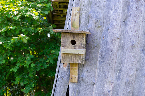 wooden barn with a wooden bird cage attached to the wall.