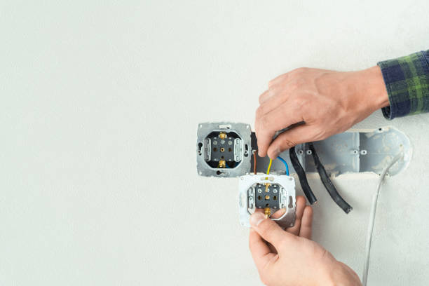istock Electrician mounts a new socket on a white wall. Renovation process in a new apartment. Free space for your text 1405176553