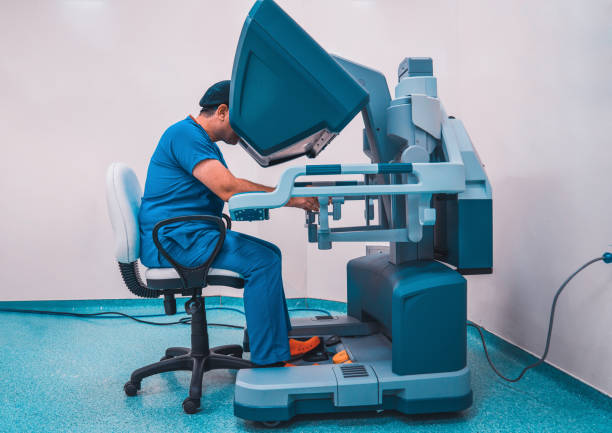 doctor posing with robotic surgical system. - robotchirurgie stockfoto's en -beelden
