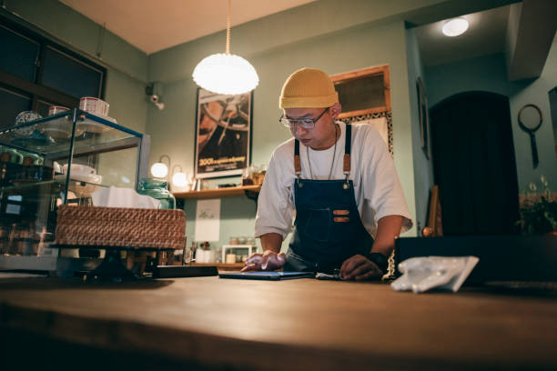 Asian man owner checking on financial bill when restaurant closed.
