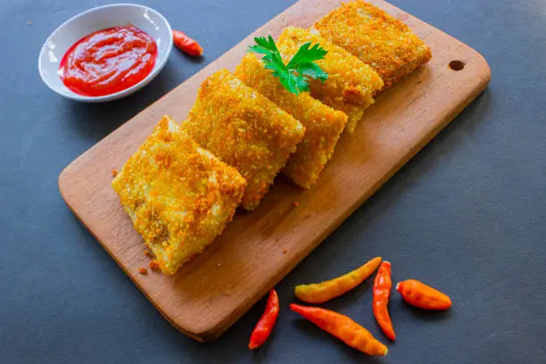 Fried Risoles or Risol Mayo are Indonesian snacks. Like Coxinha de Galinha. served with chili sauce, celery on wood board