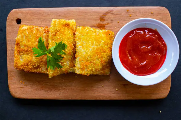 Fried Risoles or Risol Mayo are Indonesian snacks. Like Coxinha de Galinha. served with chili sauce, celery on wood board