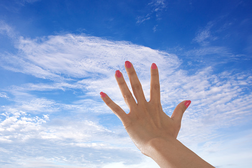 Woman hand riseing to bright blue sky reaching for hope. Closed up  only one hand riseing.
