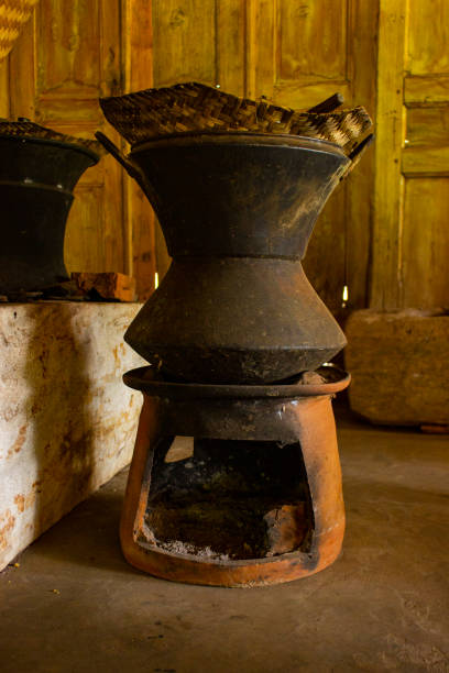 Traditional clay furnace with open fireplace. Primitive way of roasting coffee beans in steel pan at coffee farm in Bali, Indonesia. Simple production of coffee Arabica, Kopi Luwak on coffee factory.