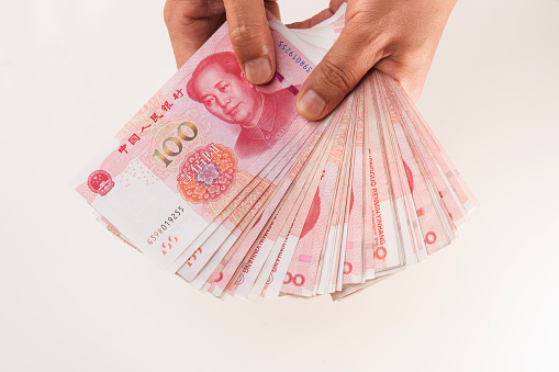 men hand fanning through large stack of china currency