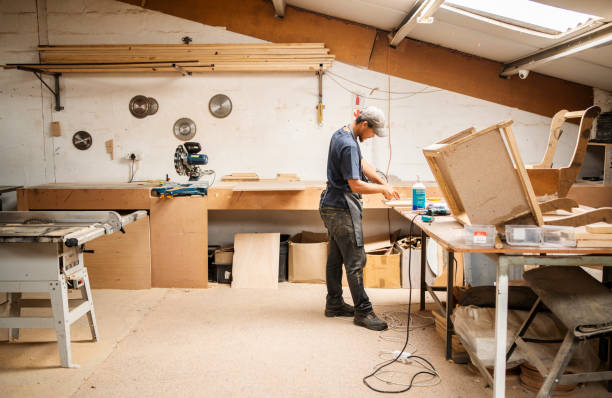 Worker assembling a chair at a bench in a furniture workshop stock photo