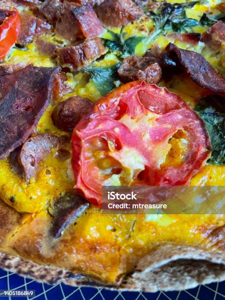Full Frame Image Of Spanish Omelette Frittata On Blue Rimmed Plate Pepperoni Slices Sausage Cherry Tomato Halves Wilted Spinach Leaves Elevated View Focus On Foreground Stock Photo - Download Image Now