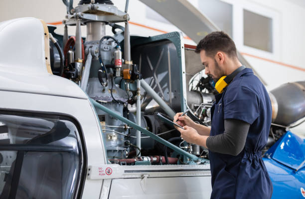 istock Male Aero Engineer With Clipboard Checking On Helicopter In Hangar 1405188698