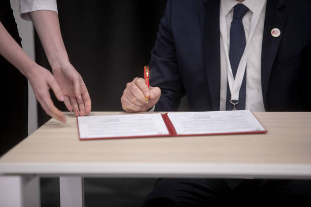 Close up young businessman standing near table with pen in hands, ready signing profitable offer agreement after checking contract terms of conditions, executive manager involved in legal paperwork. encierro joven empresario de pie cerca de la mesa con bolígrafo en las manos, listo para firmar un acuerdo de oferta rentable después de verificar los términos de condiciones del contrato, gerente ejecutivo involucrado en el papeleo legal.