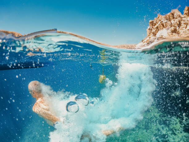 Underwater shot of diver breaking water surface after cliff jumping on sunny summer day