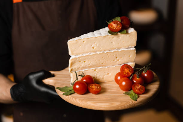 istock Cheese Sommelier holding plate with brie cheese with tomatoes. Creative idea for advertising a cheese shop. 1405199434
