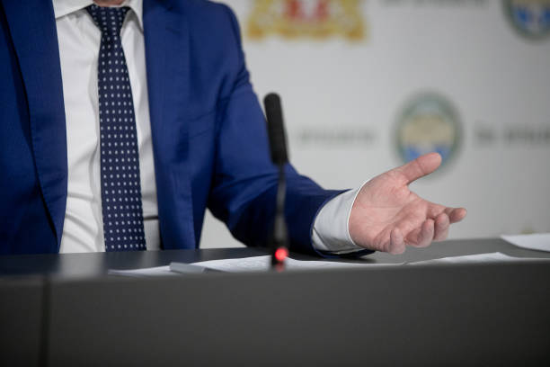 Politician with clasped hands sitting behind desk. stock photo