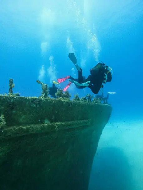 Underwater shot of two  male scuba divers exploring old, sunken shipwreck