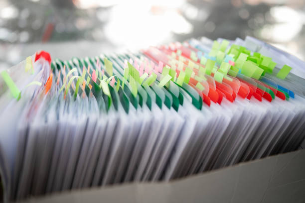 istock Stack of business report paper file on modern white office desk with bokeh background. 1405202764
