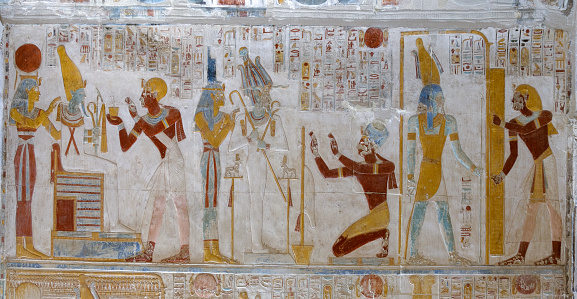 king Seti before Osiris and Isis at Abydos temple in Middle Egypt. Travel concept.