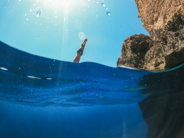 Mid adult man diving into beautiful blue sea after cliff jumping on sunny summer day