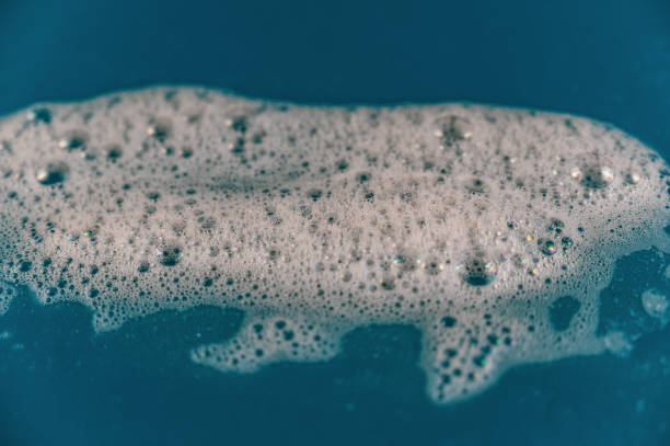 istock Soap foam against a colored background. Bubbles of white detergent foam on the blue surface. Shampoo foam texture. Selective focus. 1405212250