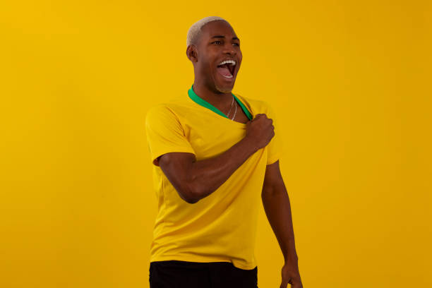 hombre brasileño de piel negra con camiseta del equipo de fútbol brasileño en foto de estudio - brasilero fotografías e imágenes de stock