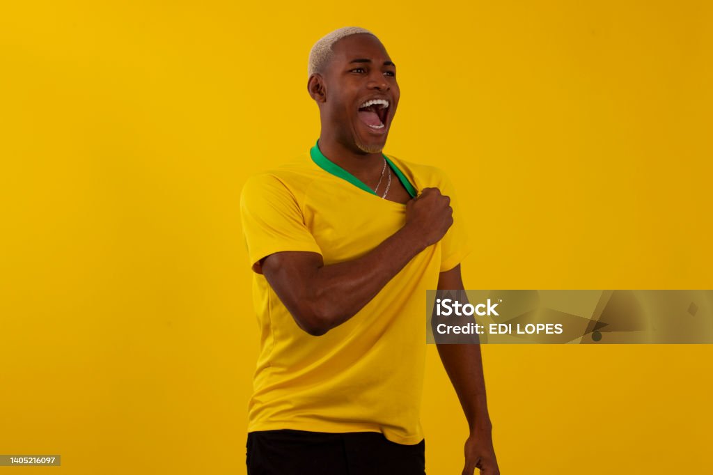 Black-skinned Brazilian man with Brazilian soccer team shirt in studio photo Fan - Enthusiast Stock Photo
